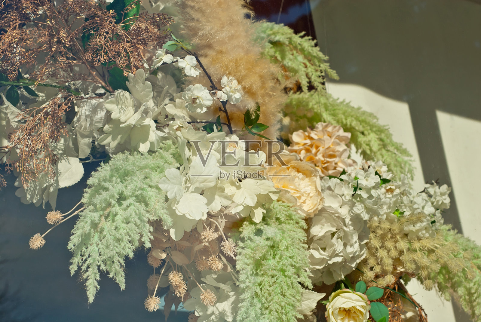 五颜六色的花朵和绿色贴在墙上。人造花装饰室内。照片摄影图片