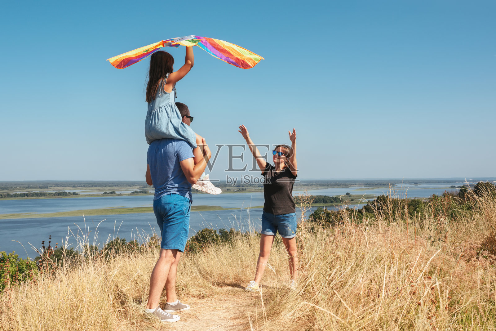 一个阳光明媚的日子，幸福的一家人带着风筝在大自然中玩耍照片摄影图片