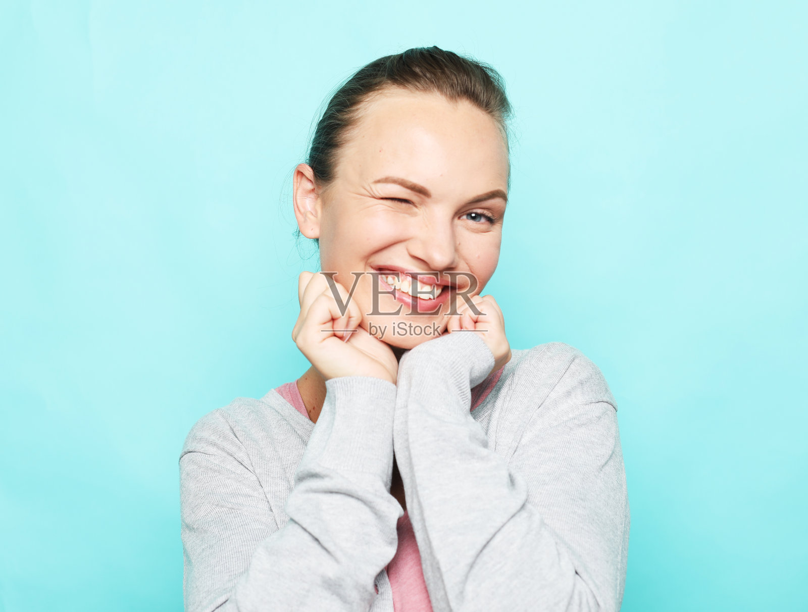 迷人的金发女人笑着享受生活。蓝色背景下穿着休闲装的女孩照片摄影图片