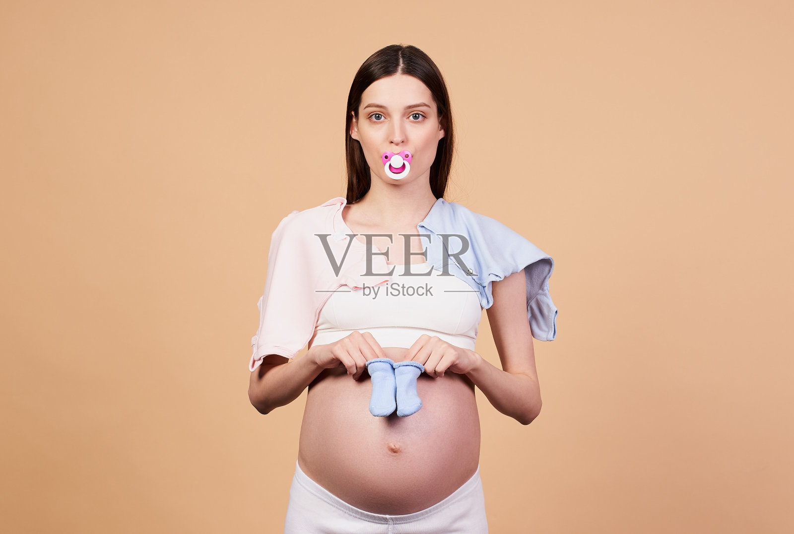 嘴里叼着奶嘴的疲惫的年轻母亲。照片摄影图片