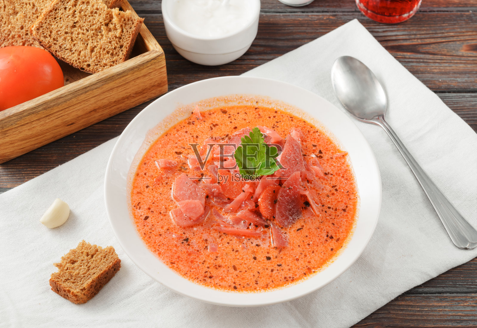 红色罗宋汤，酸奶油和欧芹，放在白色盘子里，深色木制背景，勺子，欧芹，面包，餐巾照片摄影图片