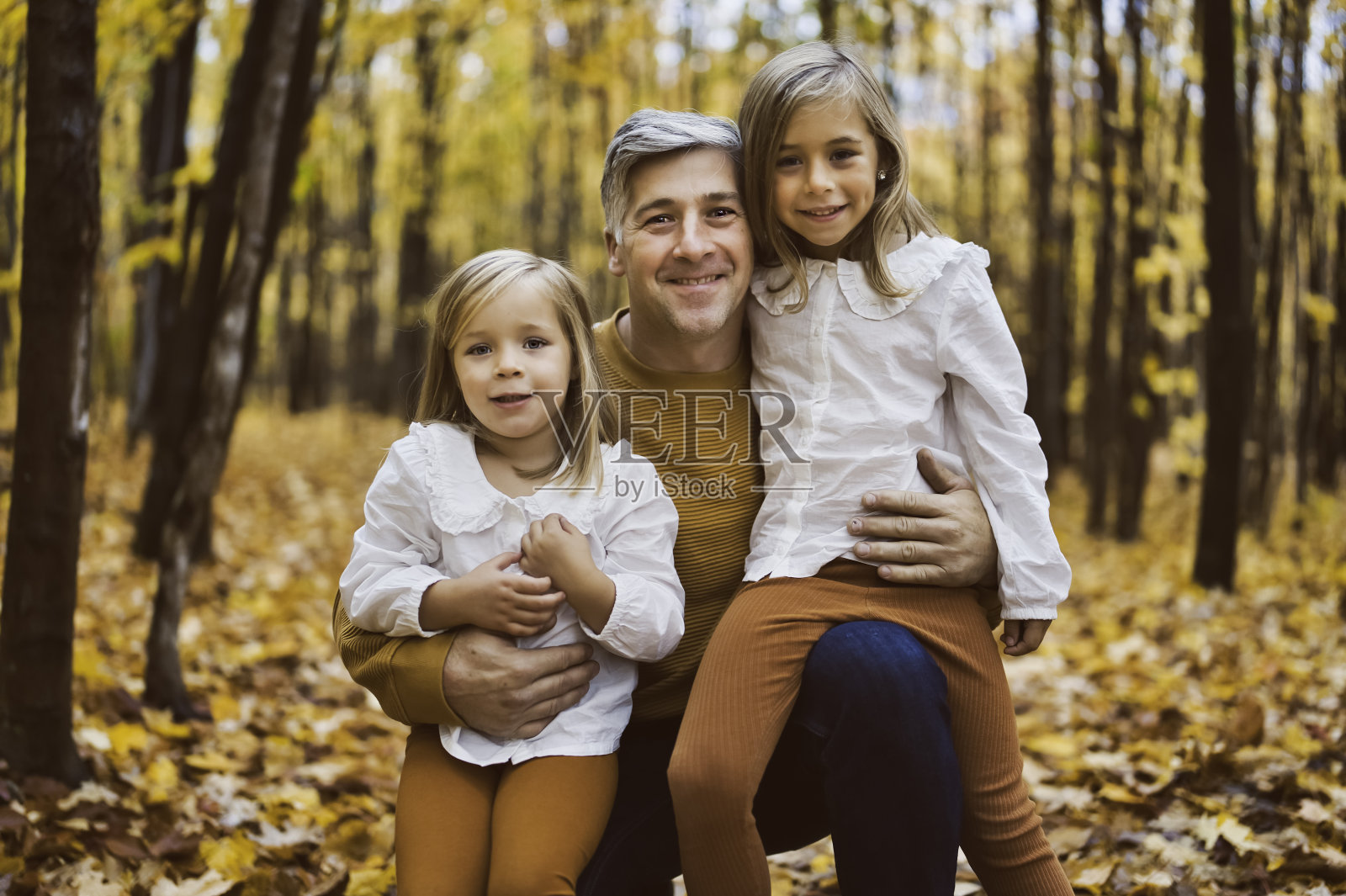 快乐的爸爸和女儿在秋天的公园里躺在黄叶上照片摄影图片