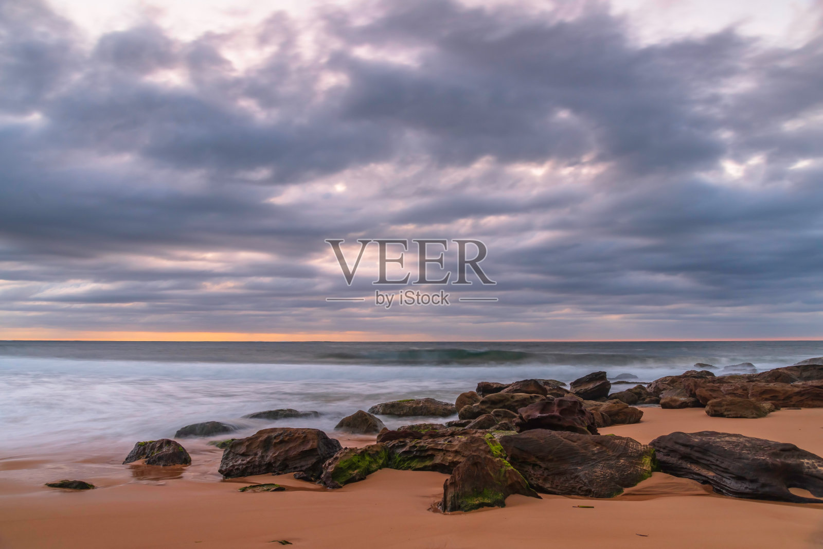 低云覆盖着日出的海景与岩石照片摄影图片