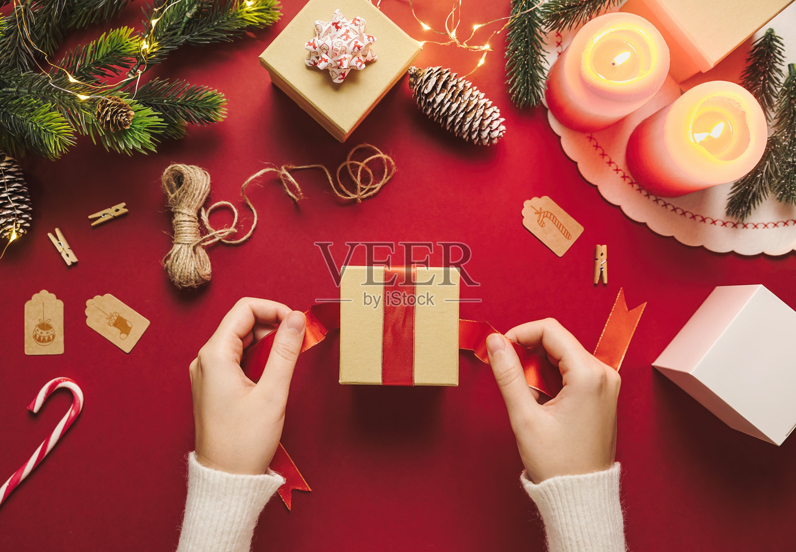 手准备和包装圣诞节礼品盒的顶部视图。圣诞快乐的乡村装饰材料红色的背景和冬季假日的概念在平。照片摄影图片