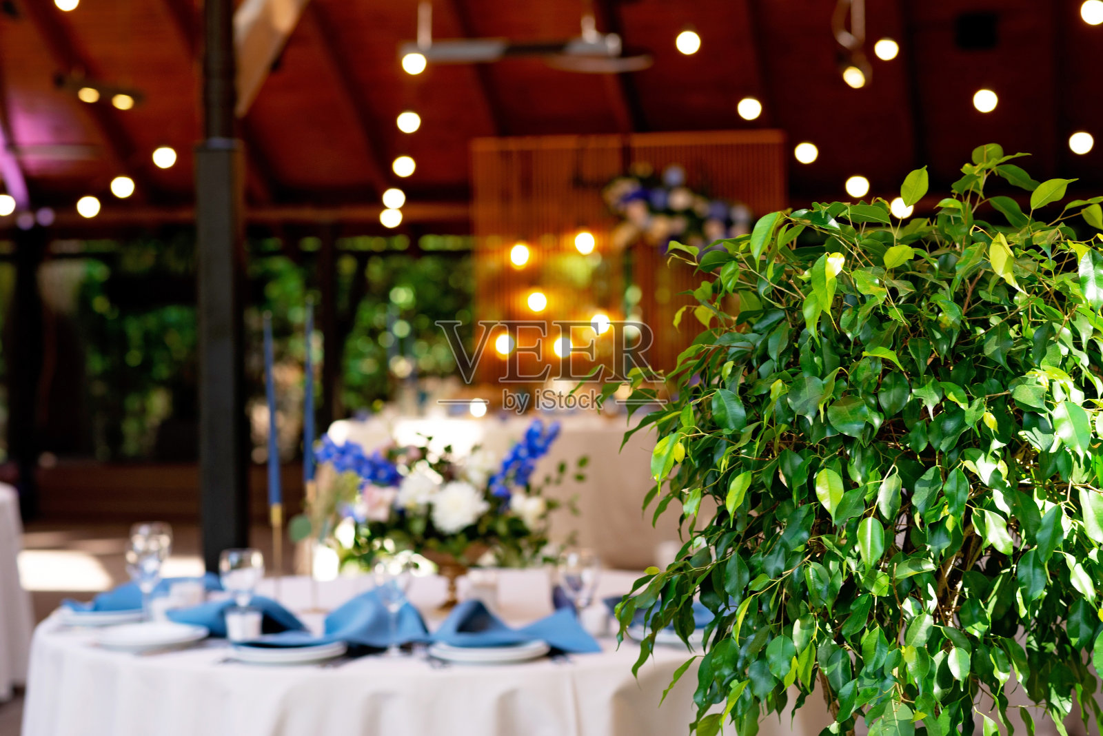 喜庆的婚礼，桌上摆放着蓝色亚麻餐巾，蜡烛和鲜花。婚礼装饰。散焦。软选择聚焦。照片摄影图片