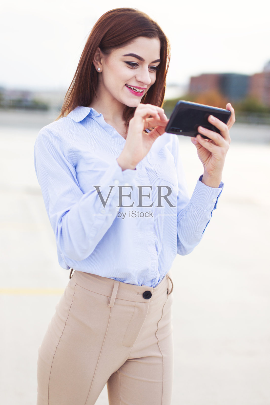 年轻的红发开朗的企业家在户外拿着智能手机照片摄影图片