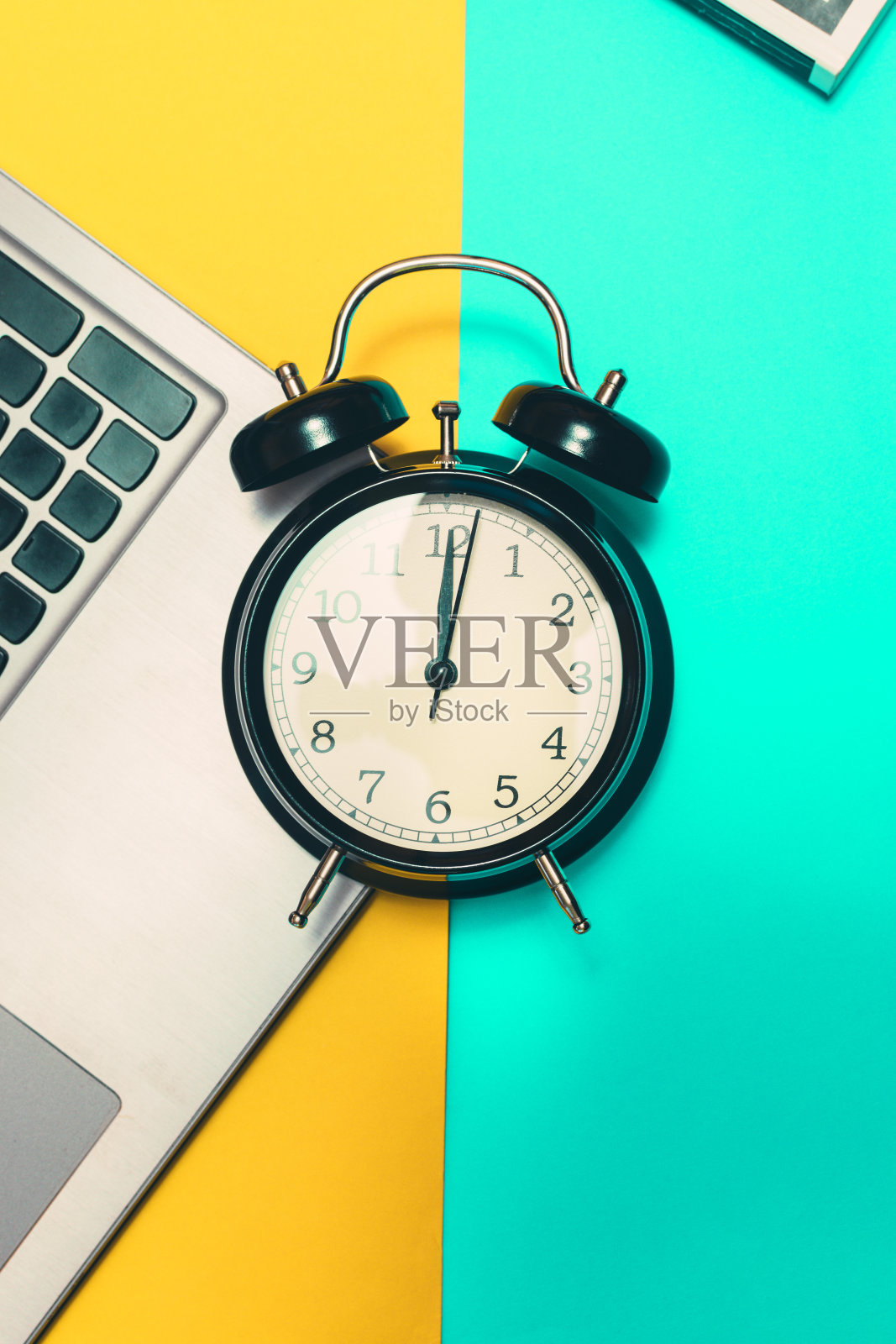 概念时间开始工作。黄色和蓝色背景的笔记本电脑闹钟。照片摄影图片