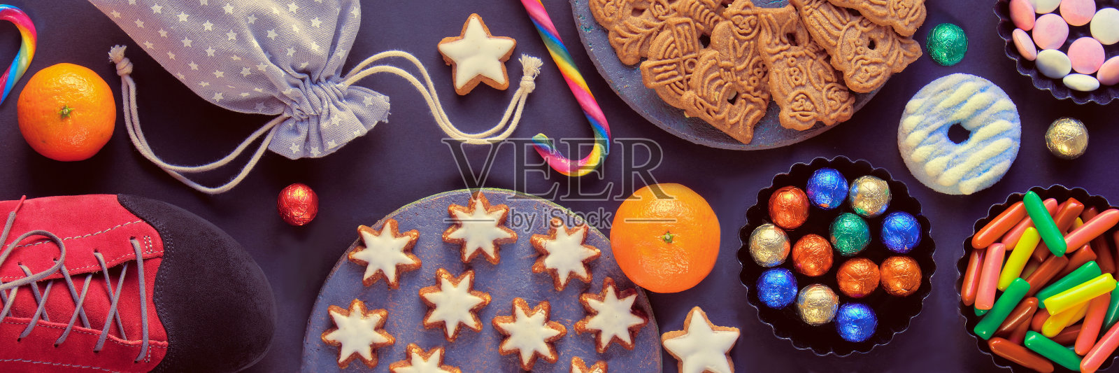 德语中的尼古拉斯日。德国和西欧的传统节日。各种糖果，糖果，饼干和一双鞋子在灰色的背景。Copy-space、文本的地方照片摄影图片