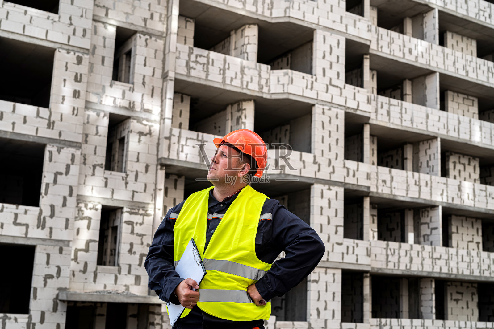 身穿制服，手拿牌匾的年轻强壮的工人正在施工现场照片摄影图片