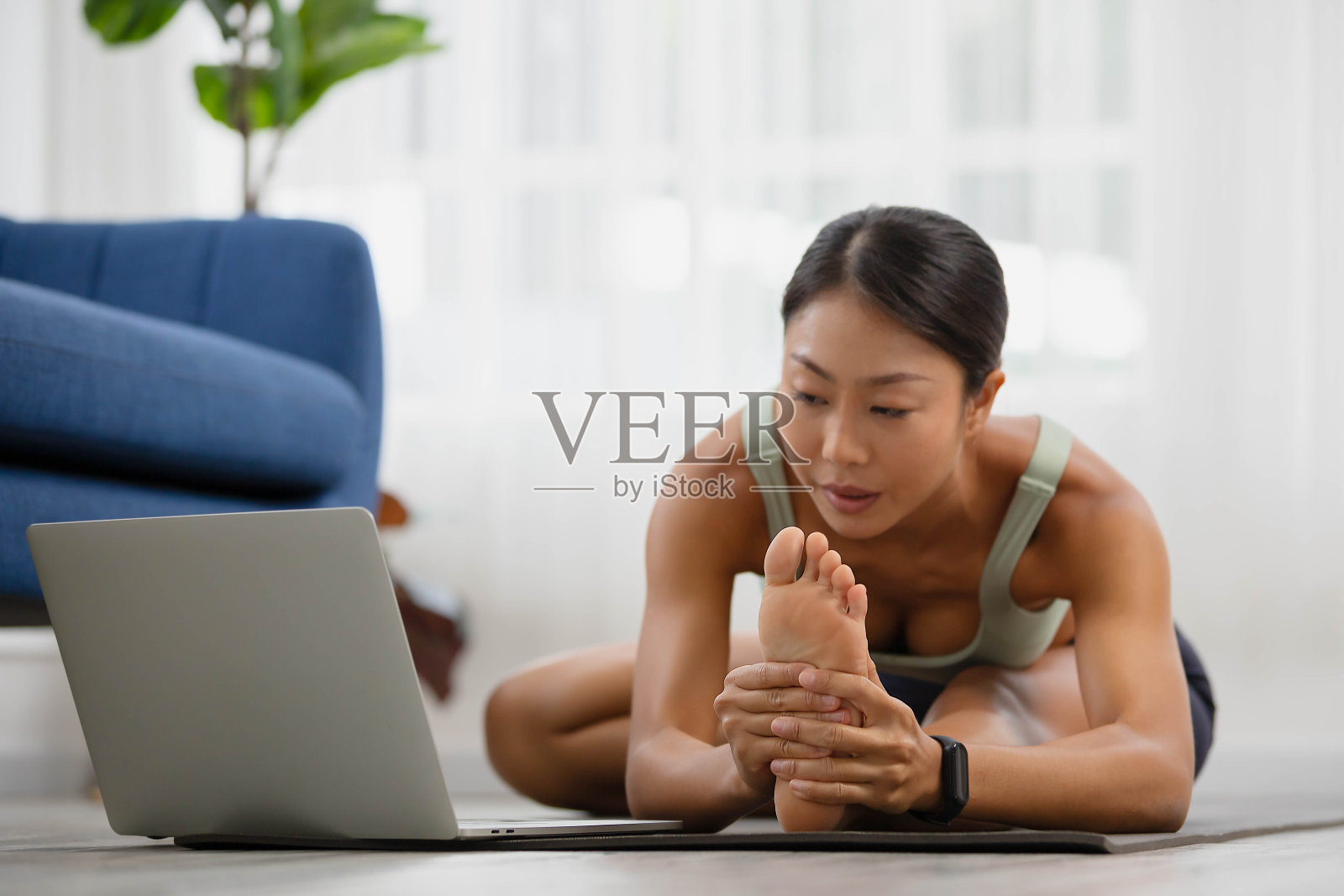 早上，一名亚洲女子在网上学习瑜伽课程，站立前屈，头对膝，uttanasana体式。照片摄影图片