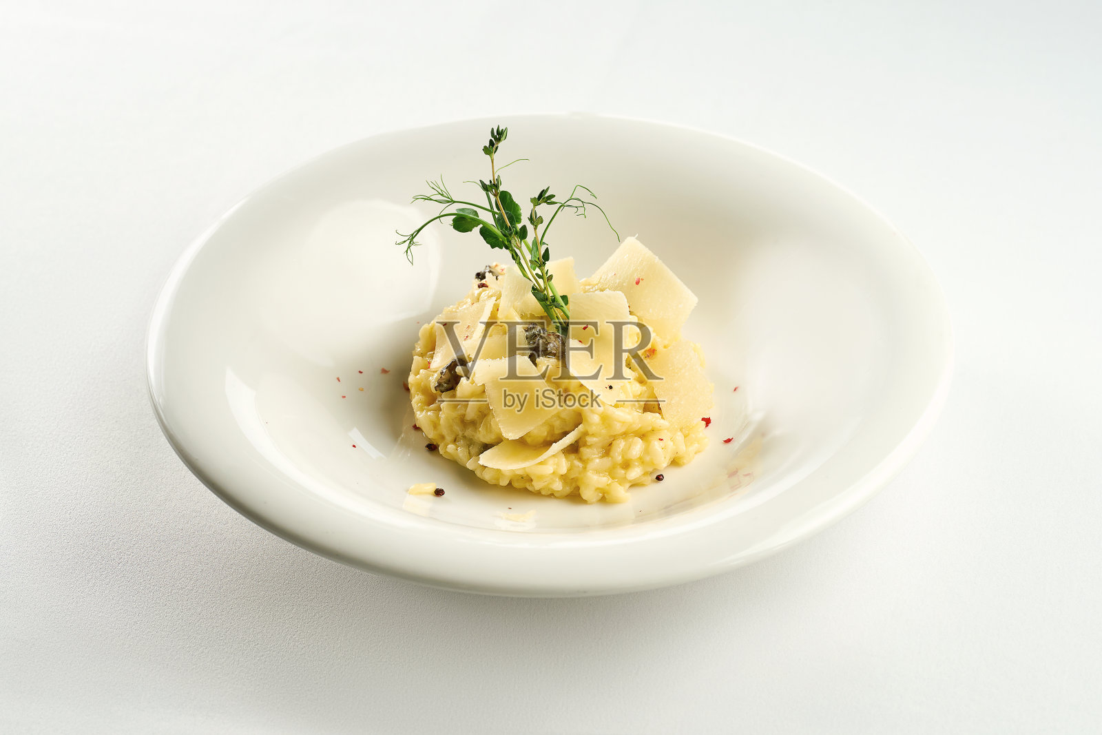 开胃的意大利烩饭，香菇和帕尔马干酪放在白色的盘子里，铺着白色的桌布照片摄影图片