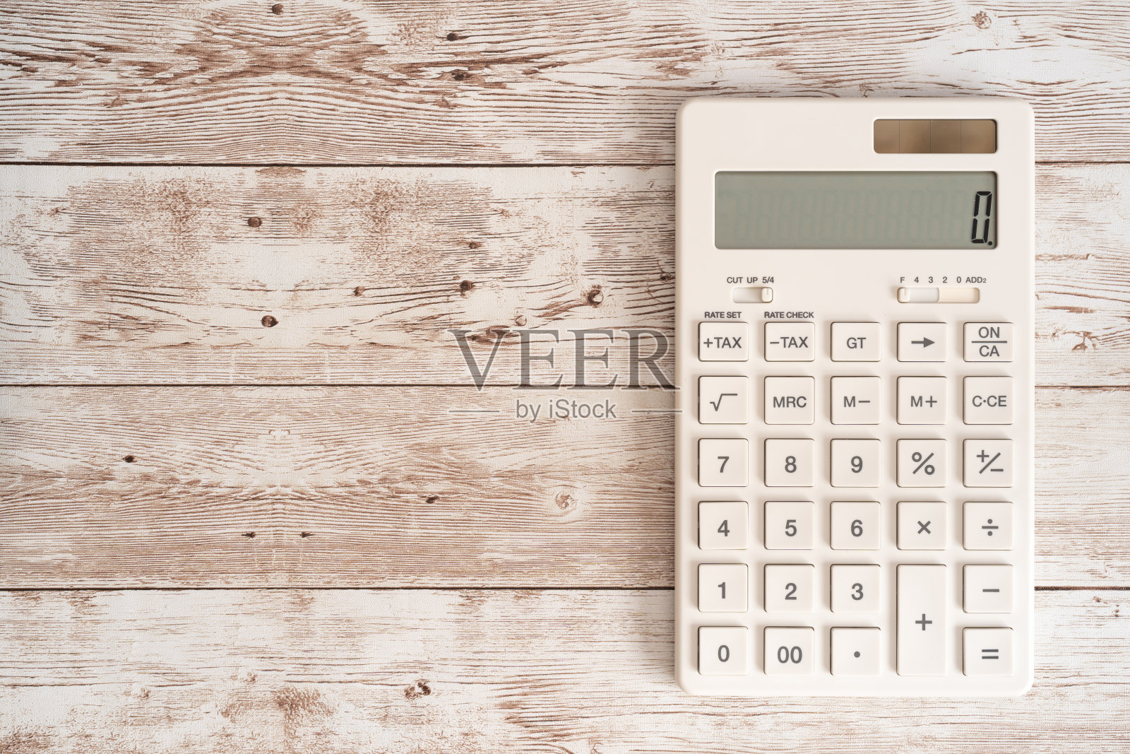 木桌上有一个白色的计算器。照片摄影图片