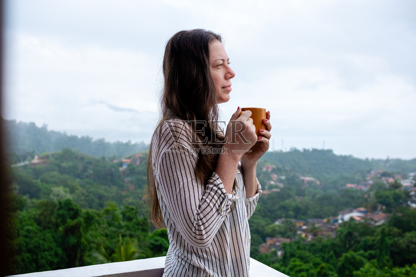 一名年轻女子在山顶上喝着茶，背景是全景照片摄影图片
