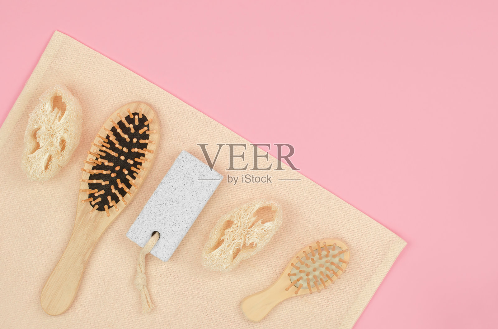 环保的个人护理产品在粉红色的背景，有文字的地方。木梳子，丝瓜络和浮石洗涤器在环保亚麻上照片摄影图片