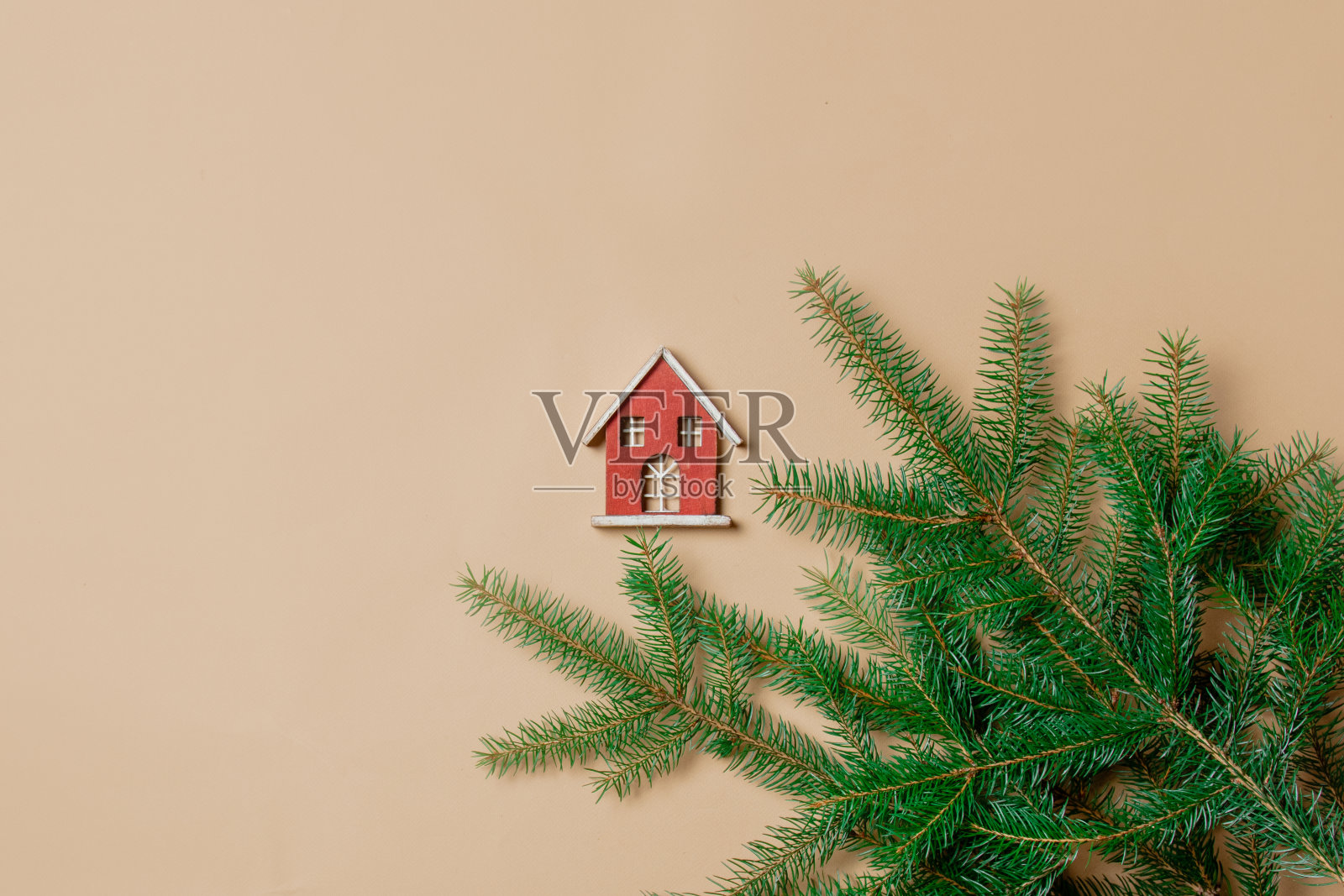 小玩具屋和云杉树枝在赤裸裸的白色背景。照片摄影图片