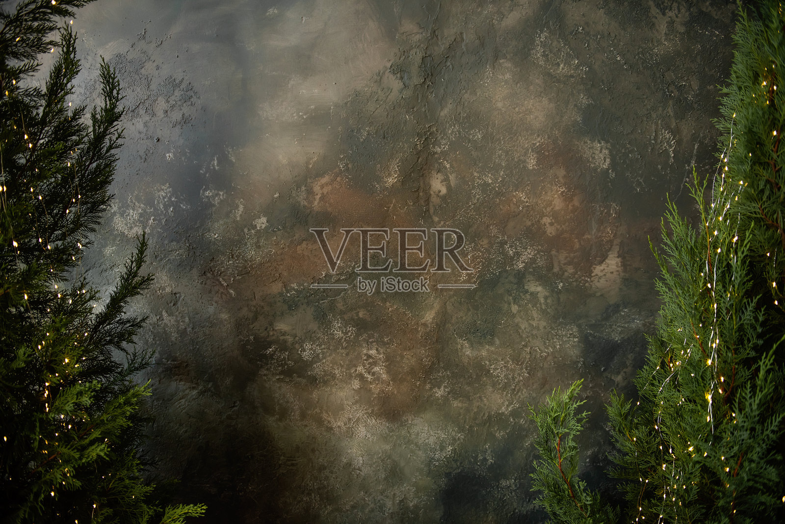 绿色的thujas和明亮的花环站在罐子里，靠着灰色的艺术垃圾墙。圣诞节的背景照片摄影图片