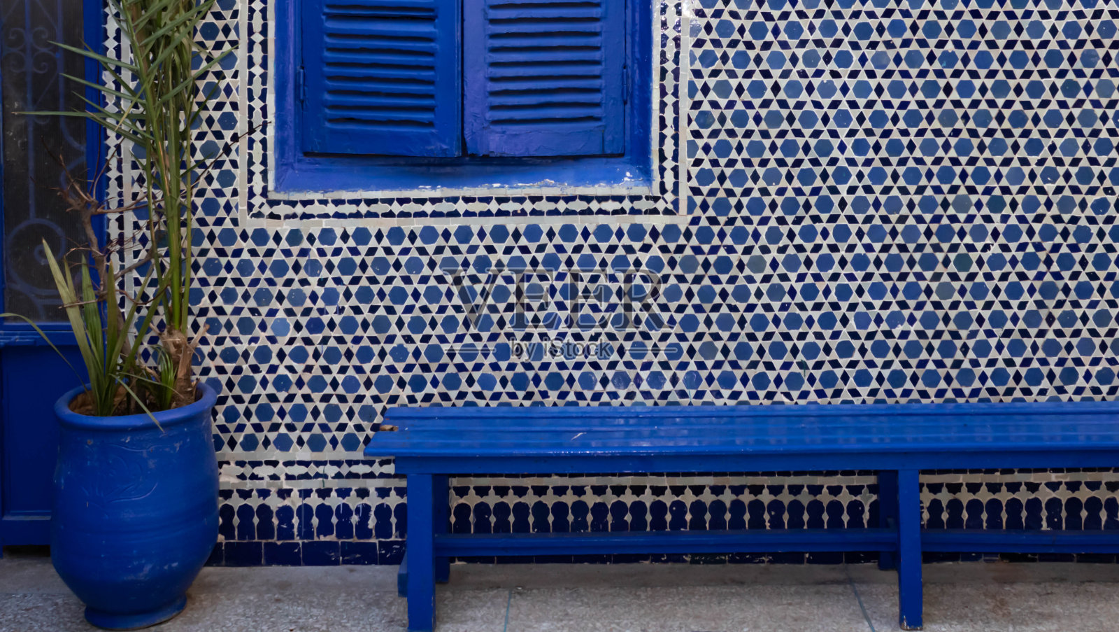 马拉喀什的蓝色花盆、长凳和蓝色瓷砖上的百叶窗照片摄影图片