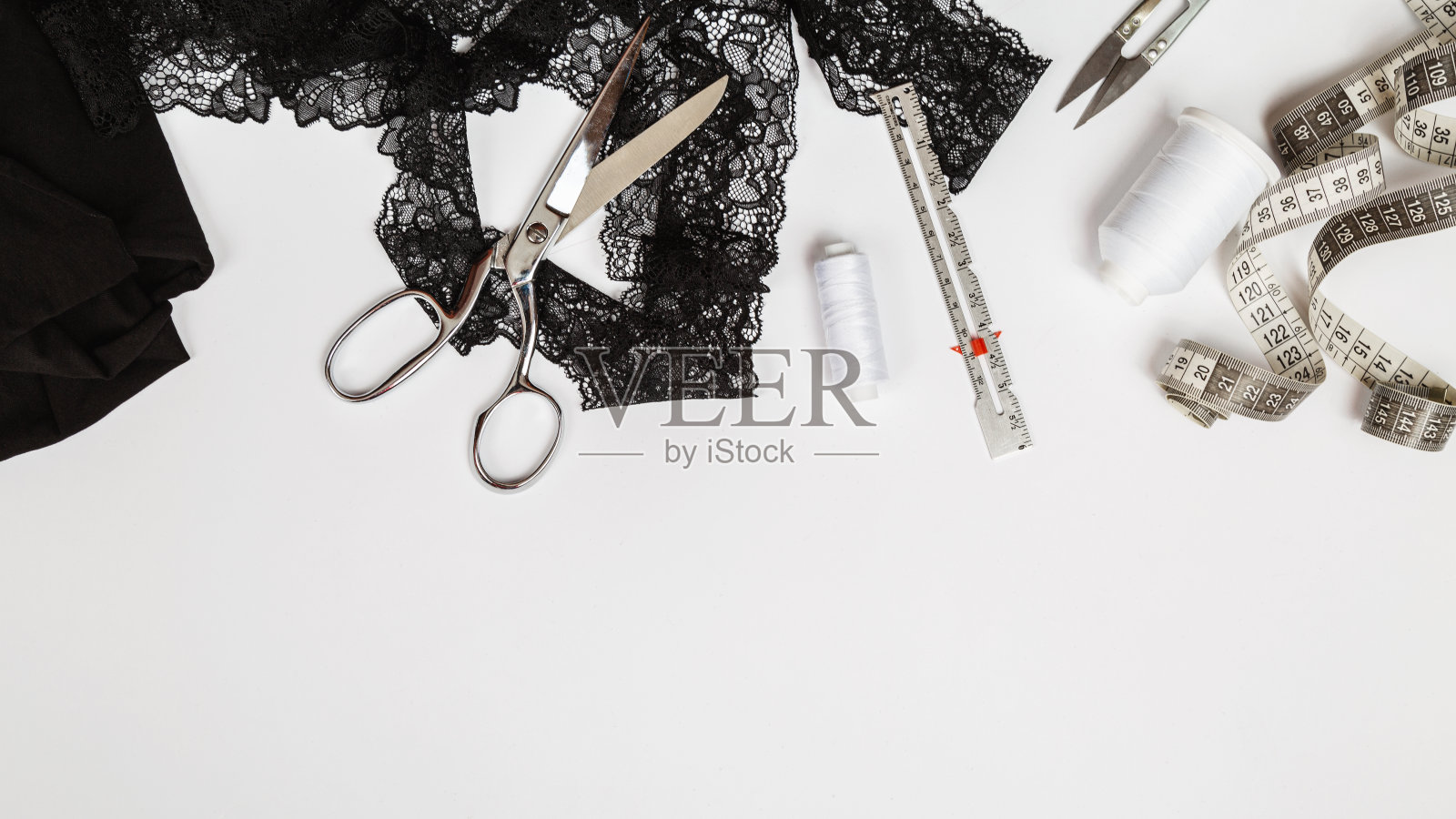 俯视图的一个女裁缝工作场所，缝纫黑色蕾丝内衣和制造它的材料躺在桌子上。照片摄影图片