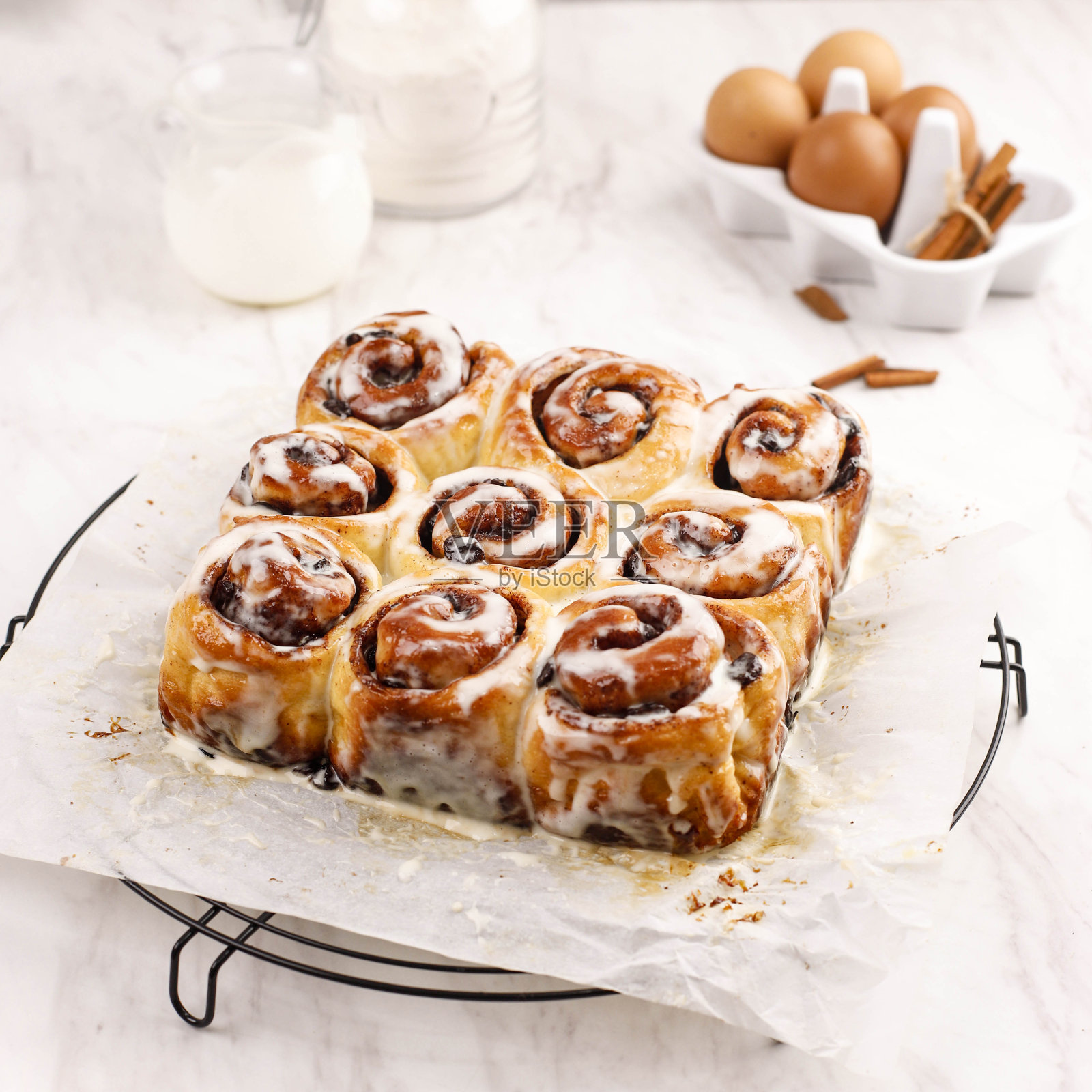 关闭肉桂卷与奶油芝士糖霜，新鲜烤在铁丝架照片摄影图片