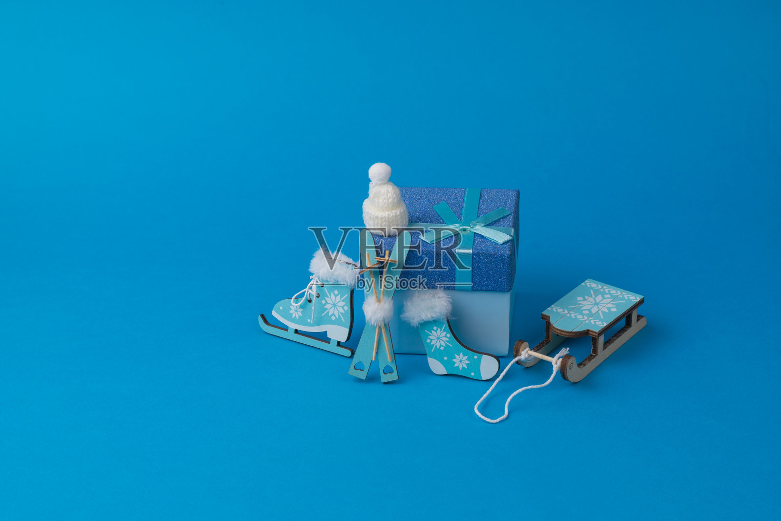 帽子，溜冰鞋，袜子，雪橇和蓝色背景上的礼盒。照片摄影图片