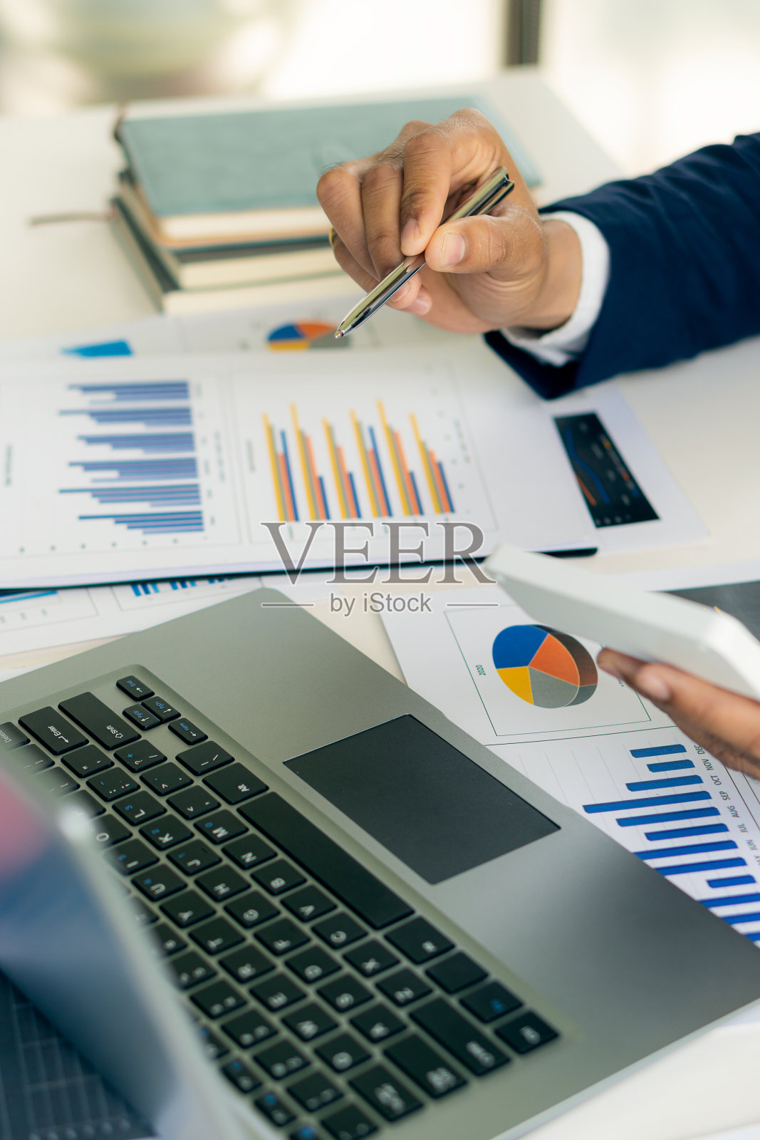 商人拿着笔指着分析纸，财务图表，以及桌上的图表。并计划投资商业和垂直特写照片股票照片摄影图片