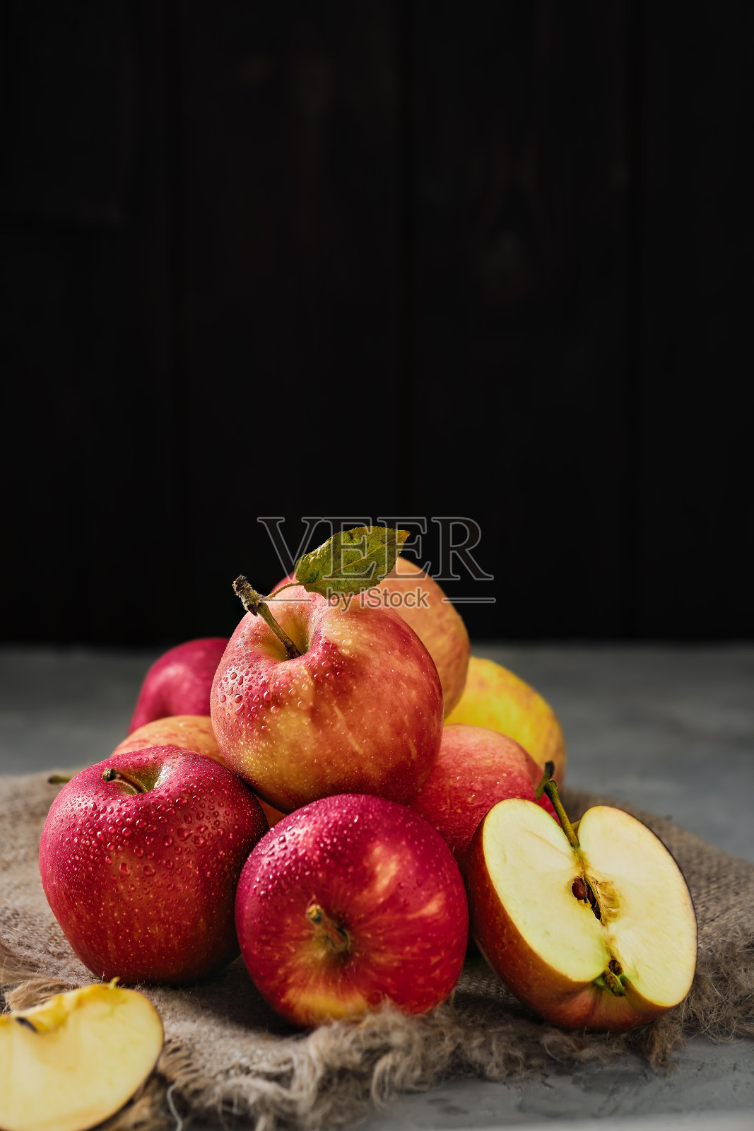 多汁的季节苹果从农场和苹果一半的水滴位于黑色木制背景。特写，选择性聚焦与复制空间。市场上有红苹果，正在收割照片摄影图片