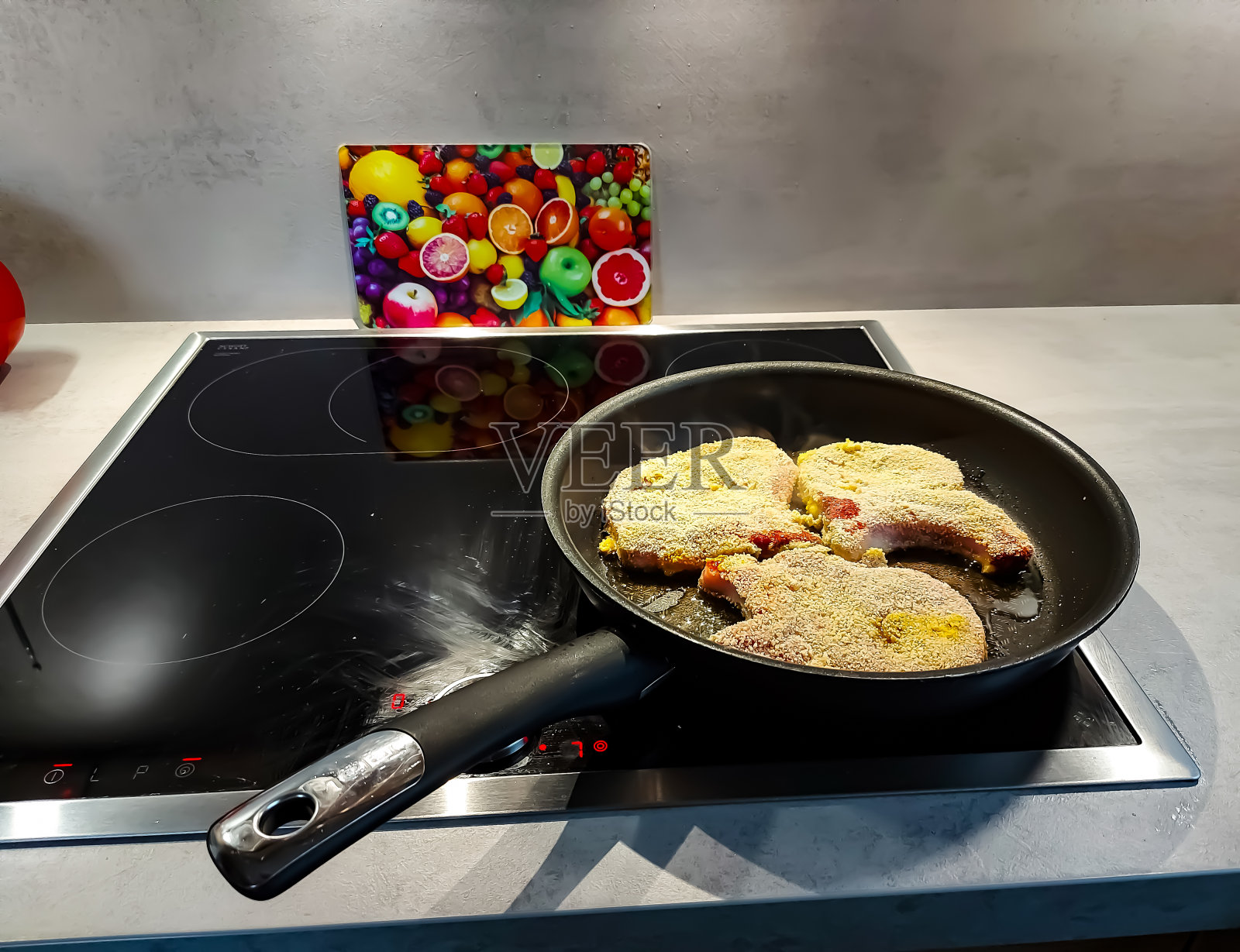 裹了面包屑的猪排在煎锅里煎照片摄影图片