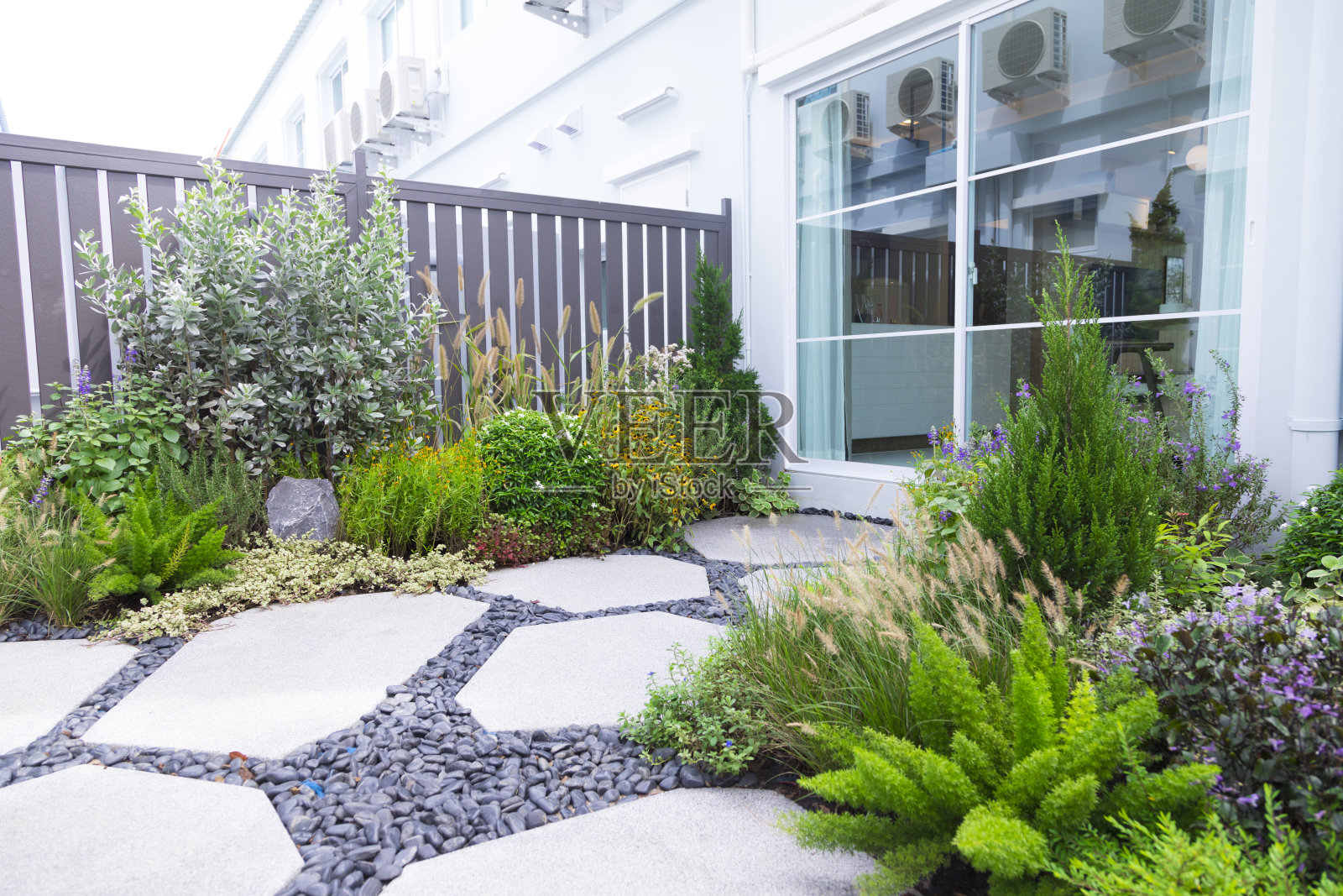小花园，有美丽的绿色花卉和植物在家里的后院花园。照片摄影图片