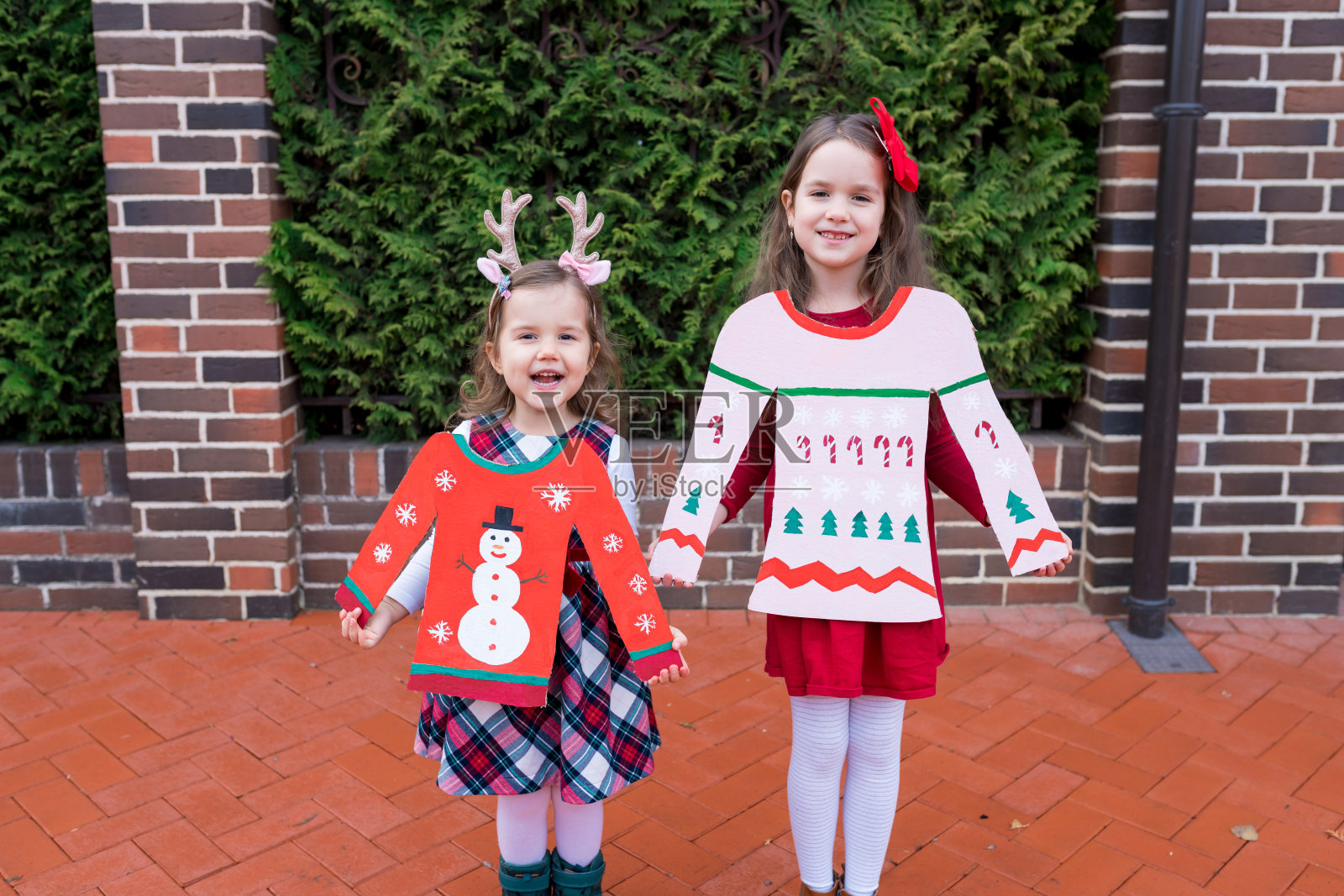 穿着丑圣诞毛衣的搞笑女孩。假日零垃圾工艺品与孩子。孩子们把这些盒子回收成有趣的创意圣诞diy概念照片摄影图片