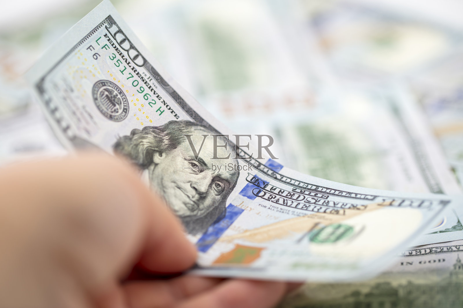 手里拿着100美元的钞票照片摄影图片