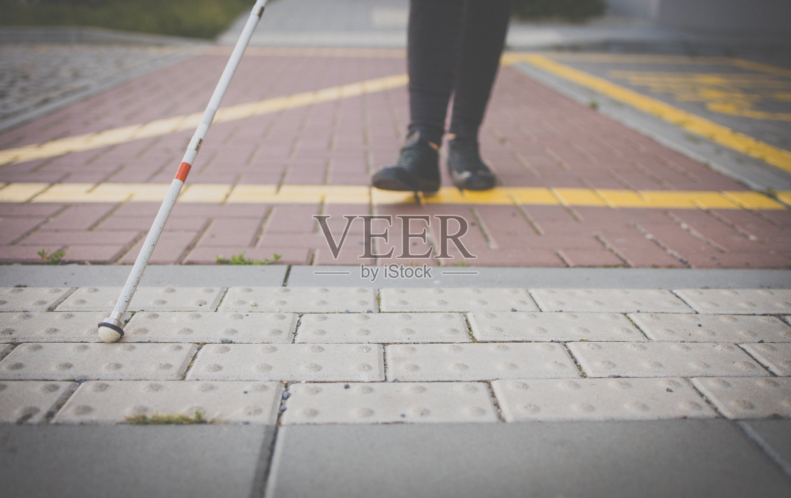 一个盲人妇女拄着白色拐杖走在城市的街道上照片摄影图片