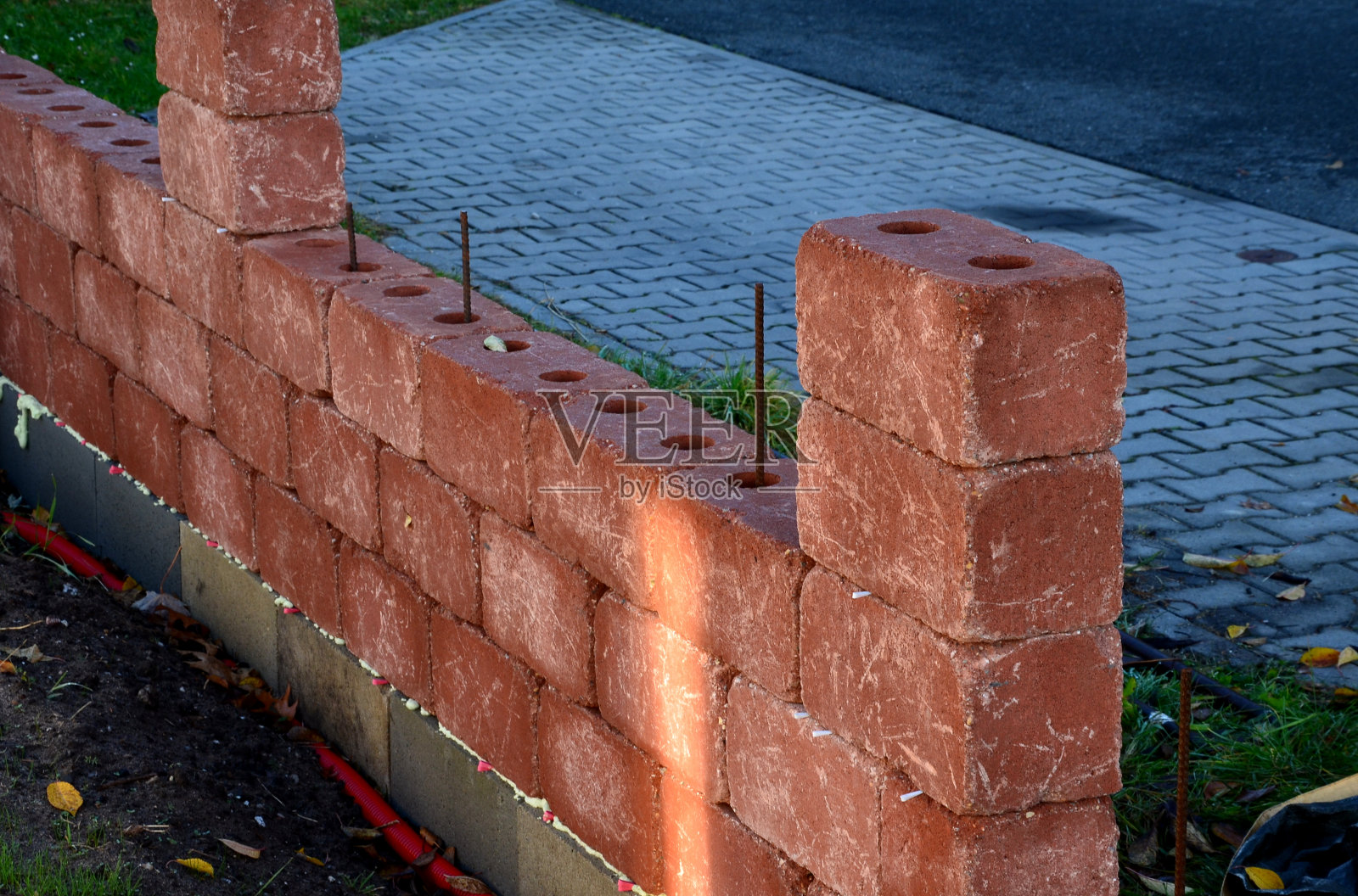 用混凝土配件建造围栏。红砖内部有插入钢筋和填充混凝土浆的孔。坚固和廉价的栅栏，由可见的颜色照片摄影图片