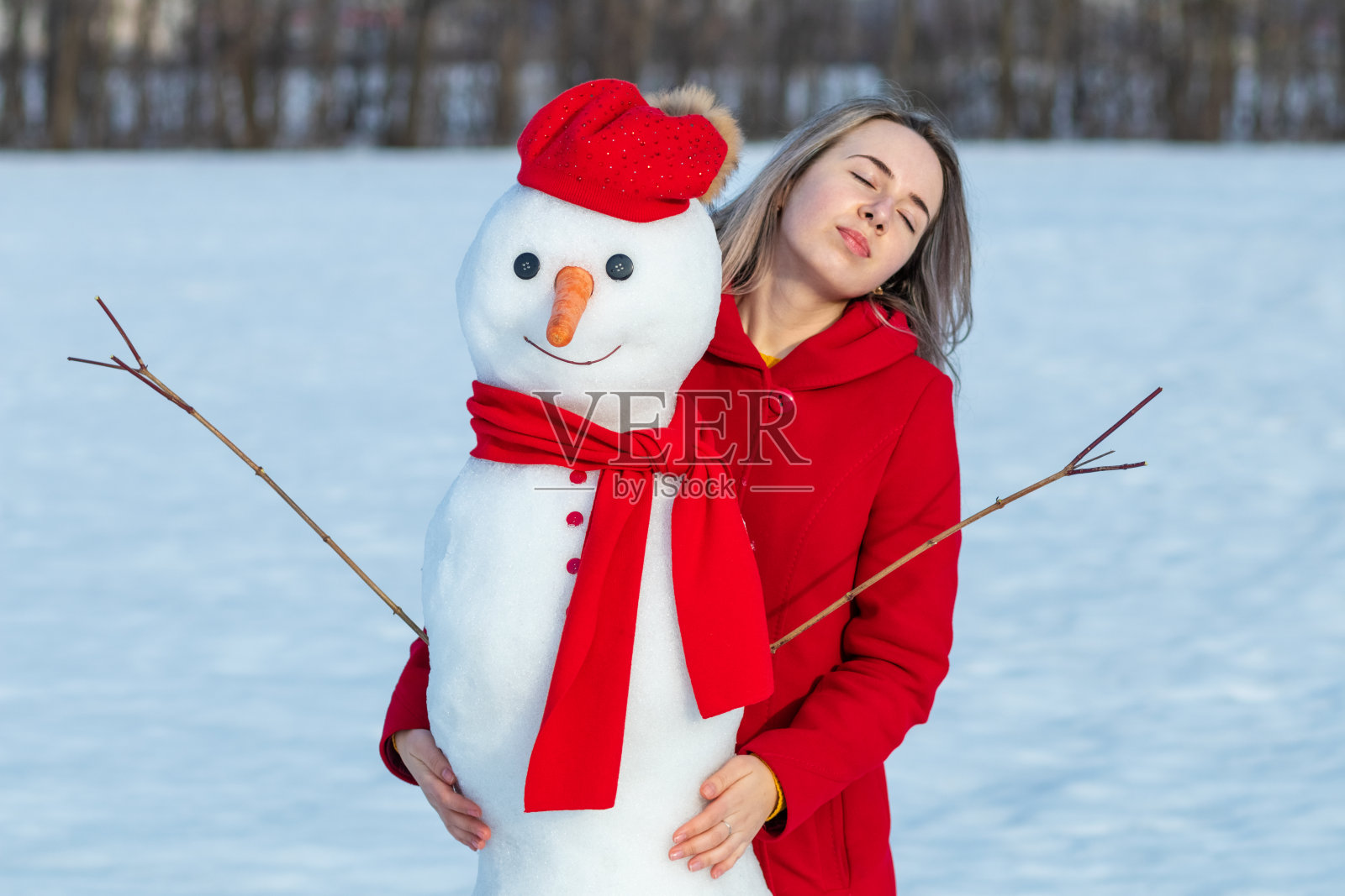 穿着红色外套的美女温柔地拥抱着雪人照片摄影图片