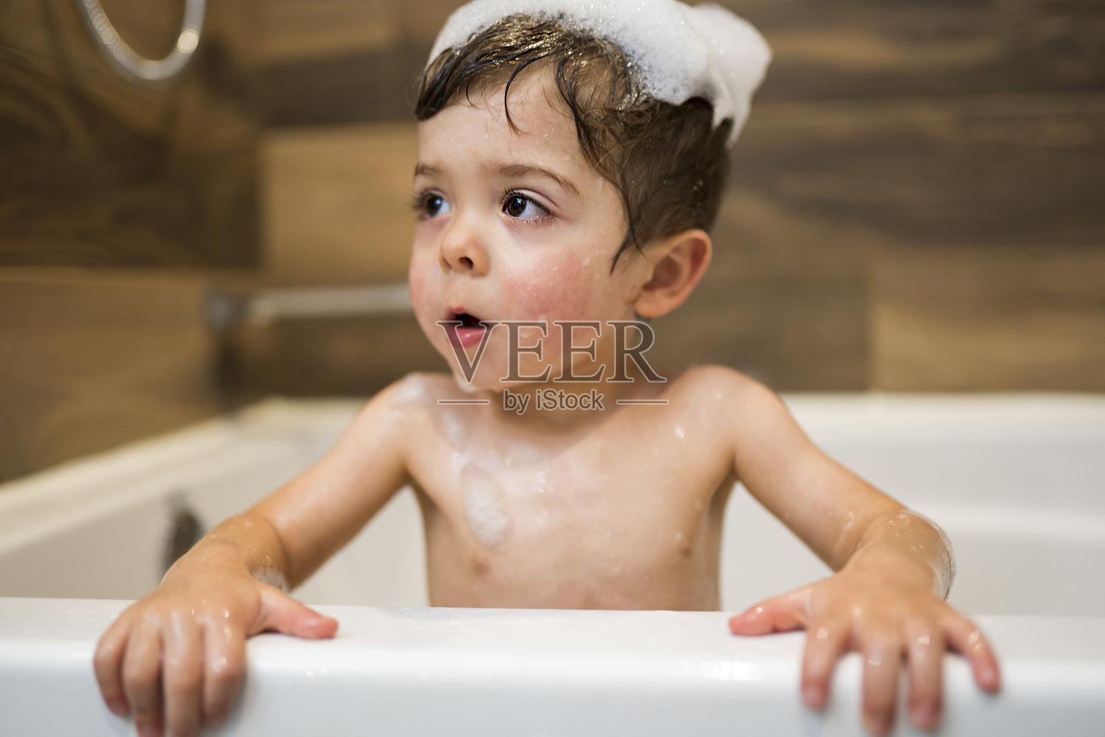 快乐的两岁孩子沐浴在玩具与泡沫浴照片摄影图片