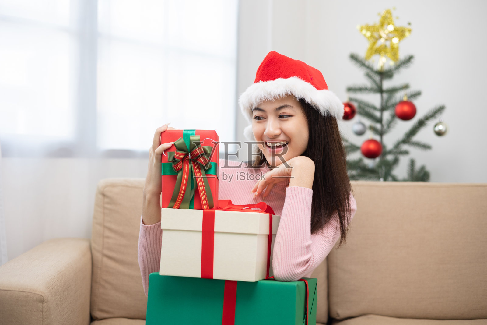 快乐美丽的亚洲女人庆祝与堆积许多礼物礼盒在圣诞晚会。可爱的女孩在圣诞假期拿着用丝带和蝴蝶结装饰的礼盒。新年佳节快乐。照片摄影图片