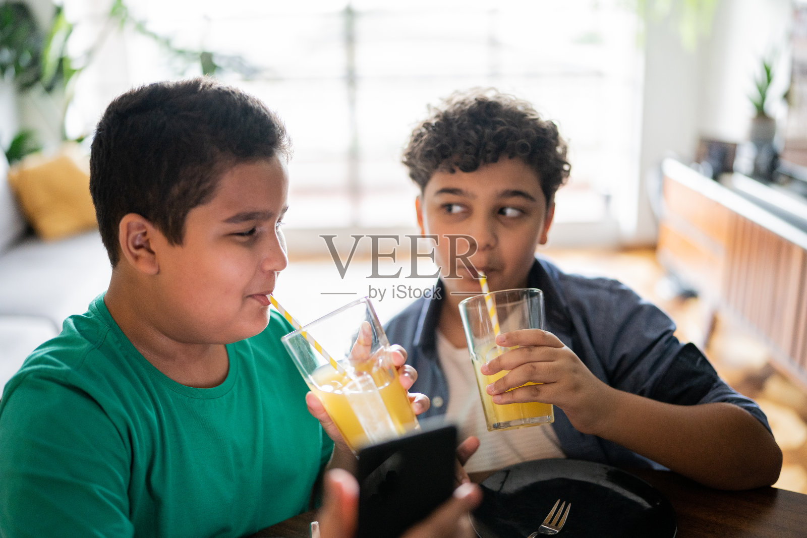 兄弟们在家里用智能手机喝果汁照片摄影图片