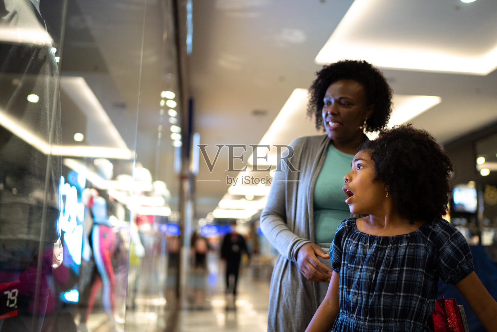母亲和女儿在购物中心看商店的橱窗照片摄影图片