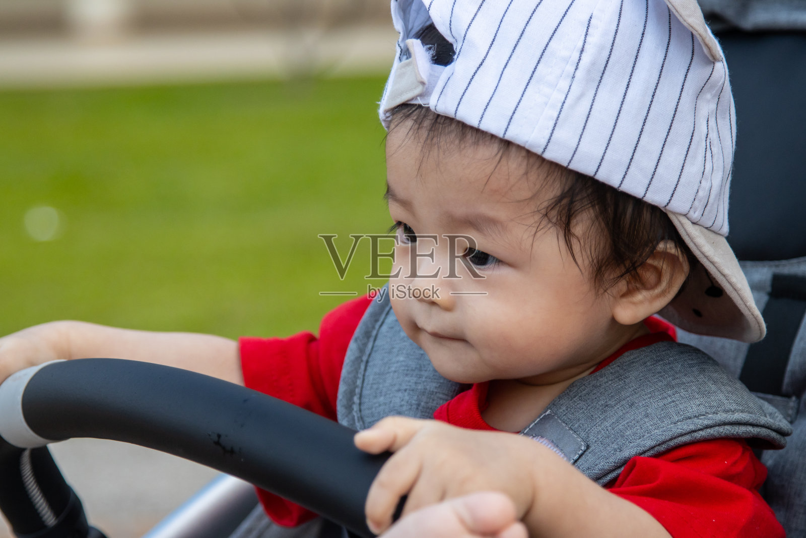 晚上在公园里，一个快乐可爱的亚洲男孩坐在婴儿车里照片摄影图片