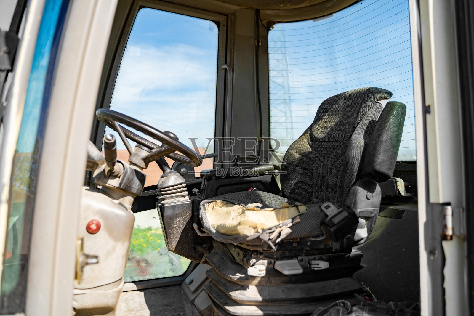 一个农场里拖拉机、起重机驾驶室里破旧、空无一人的驾驶座照片摄影图片