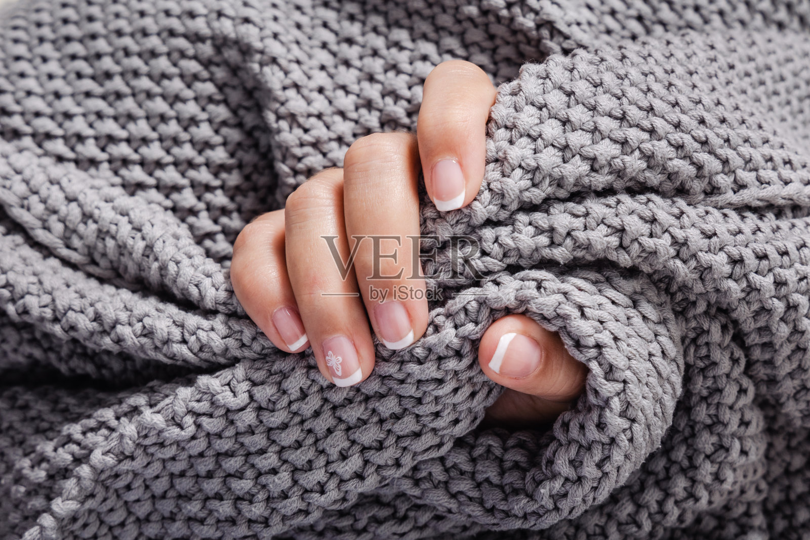 一个女人的手指抓住了一条灰色的毯子照片摄影图片