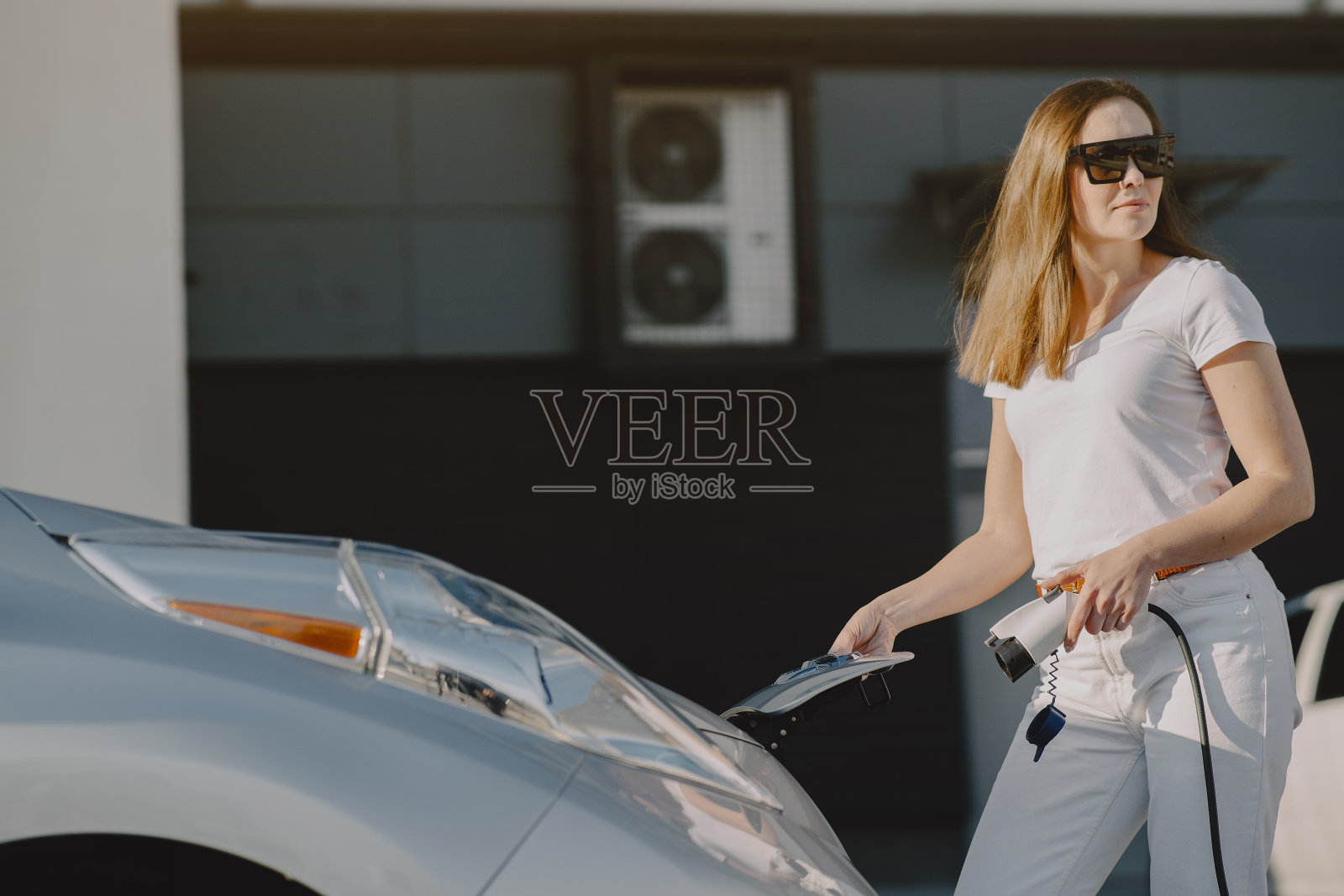 一名妇女在加油站给电动汽车充电照片摄影图片