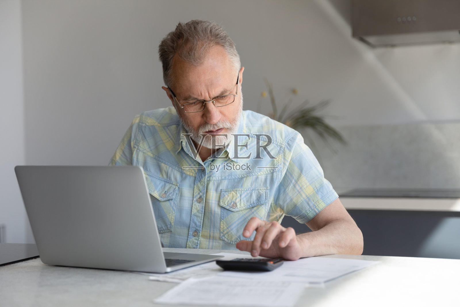 中年退休男子集中计算家庭支出。照片摄影图片