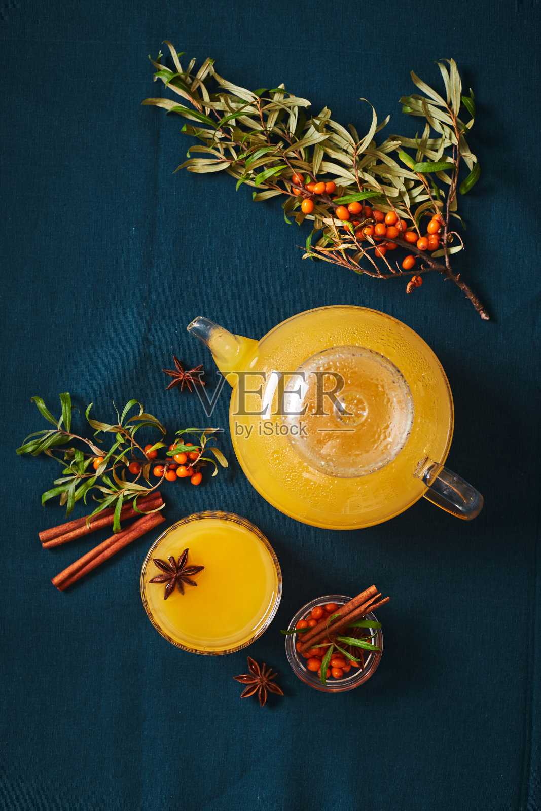 玻璃茶壶和一杯沙棘茶肉桂棒和八角在蓝色背景照片摄影图片
