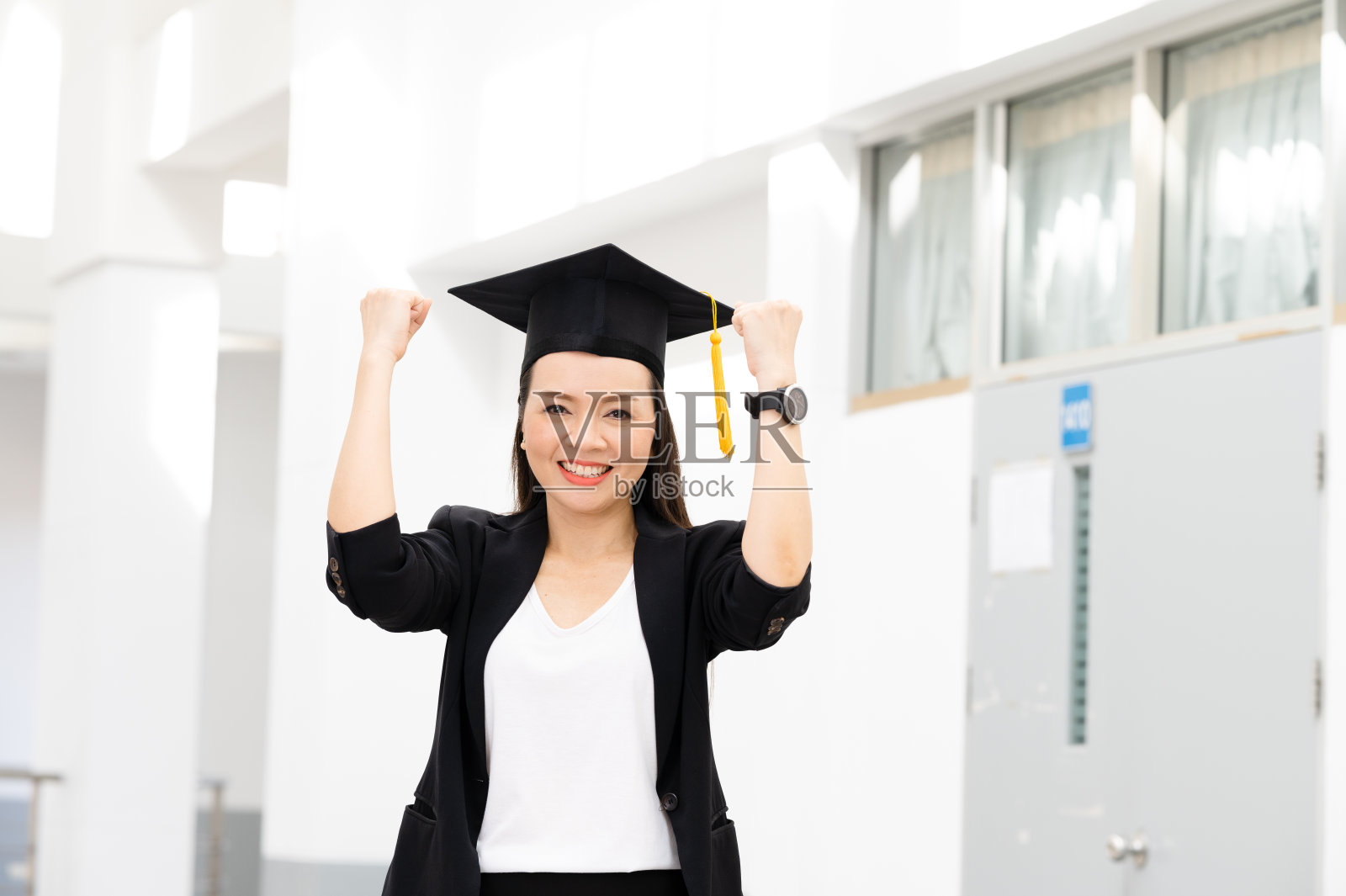 戴着黄流苏黑毕业帽的女博士毕业生们在大学里。照片摄影图片