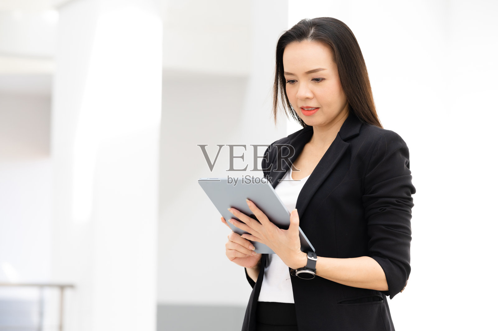 一位中年亚洲女商人，手持平板电脑对着镜头微笑照片摄影图片