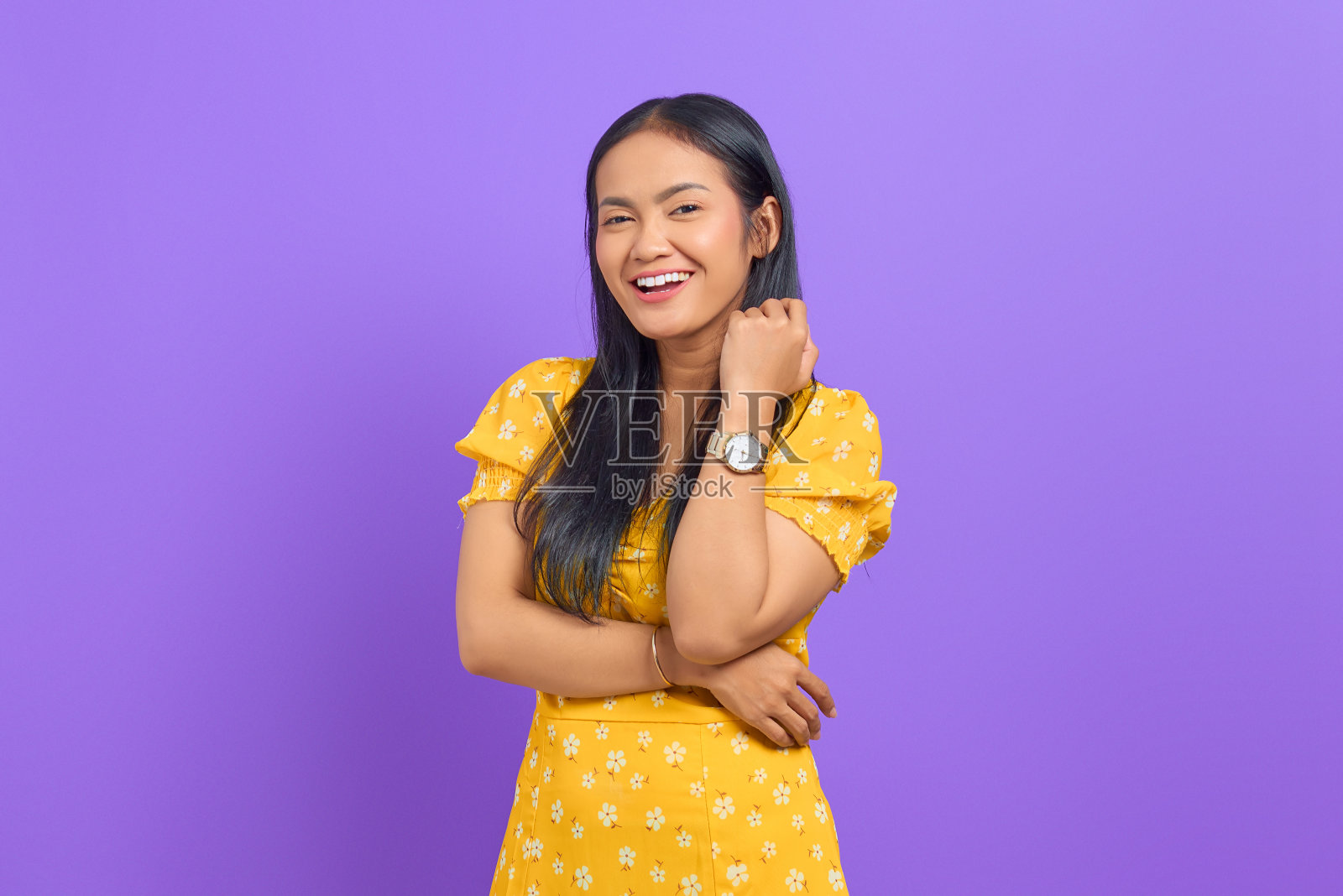 微笑的年轻亚洲妇女的肖像与交叉的手臂在紫色的背景上举起手照片摄影图片