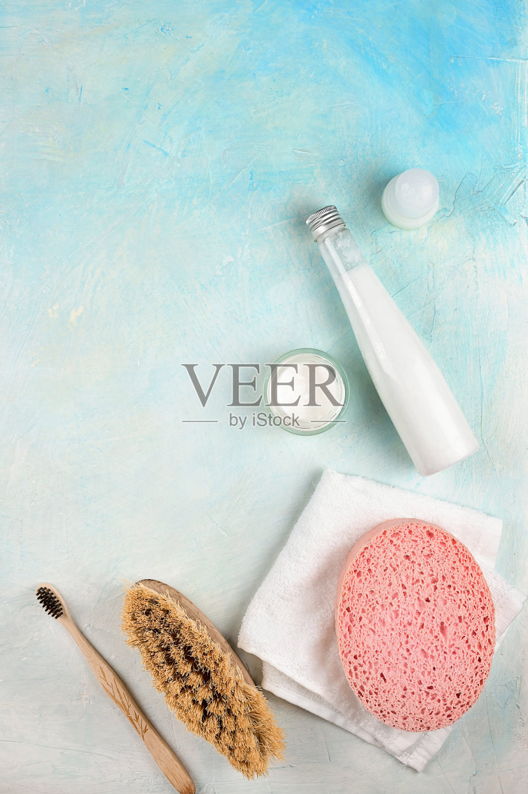 水疗设施和保健用品，椰子身体油，乳液，海绵，浴盐和毛巾在蓝色的背景照片摄影图片