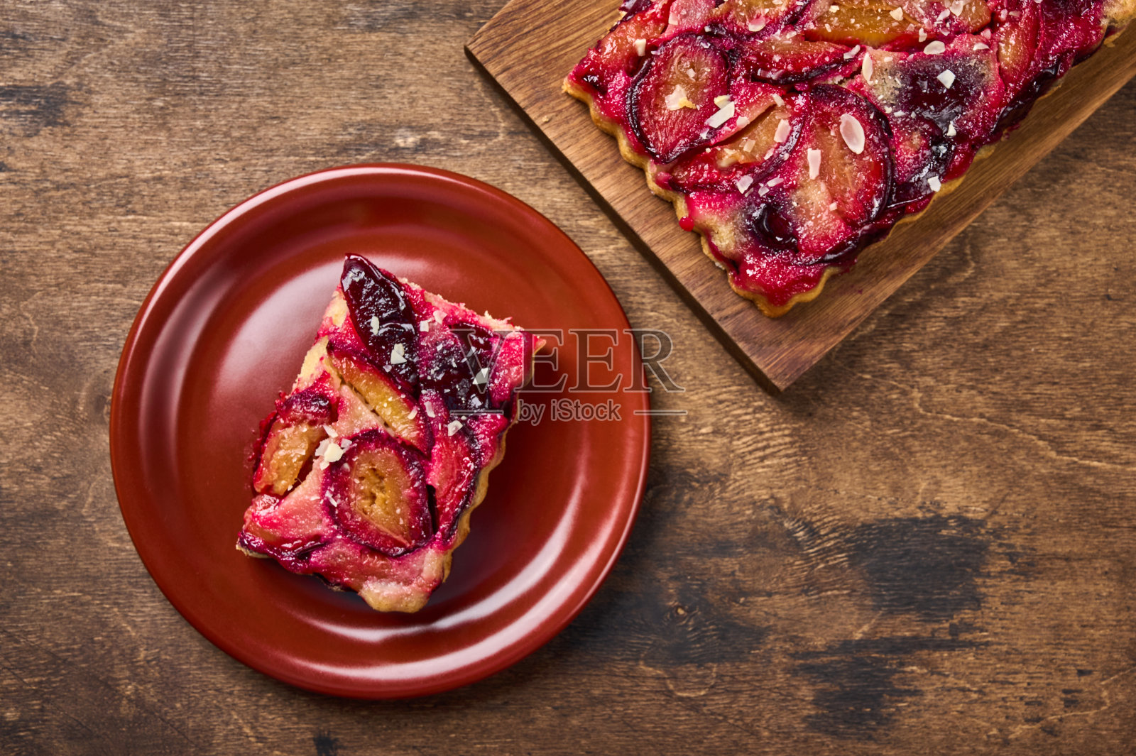 一块李子挞放在陶瓷盘上，旁边的馅饼放在木板上照片摄影图片