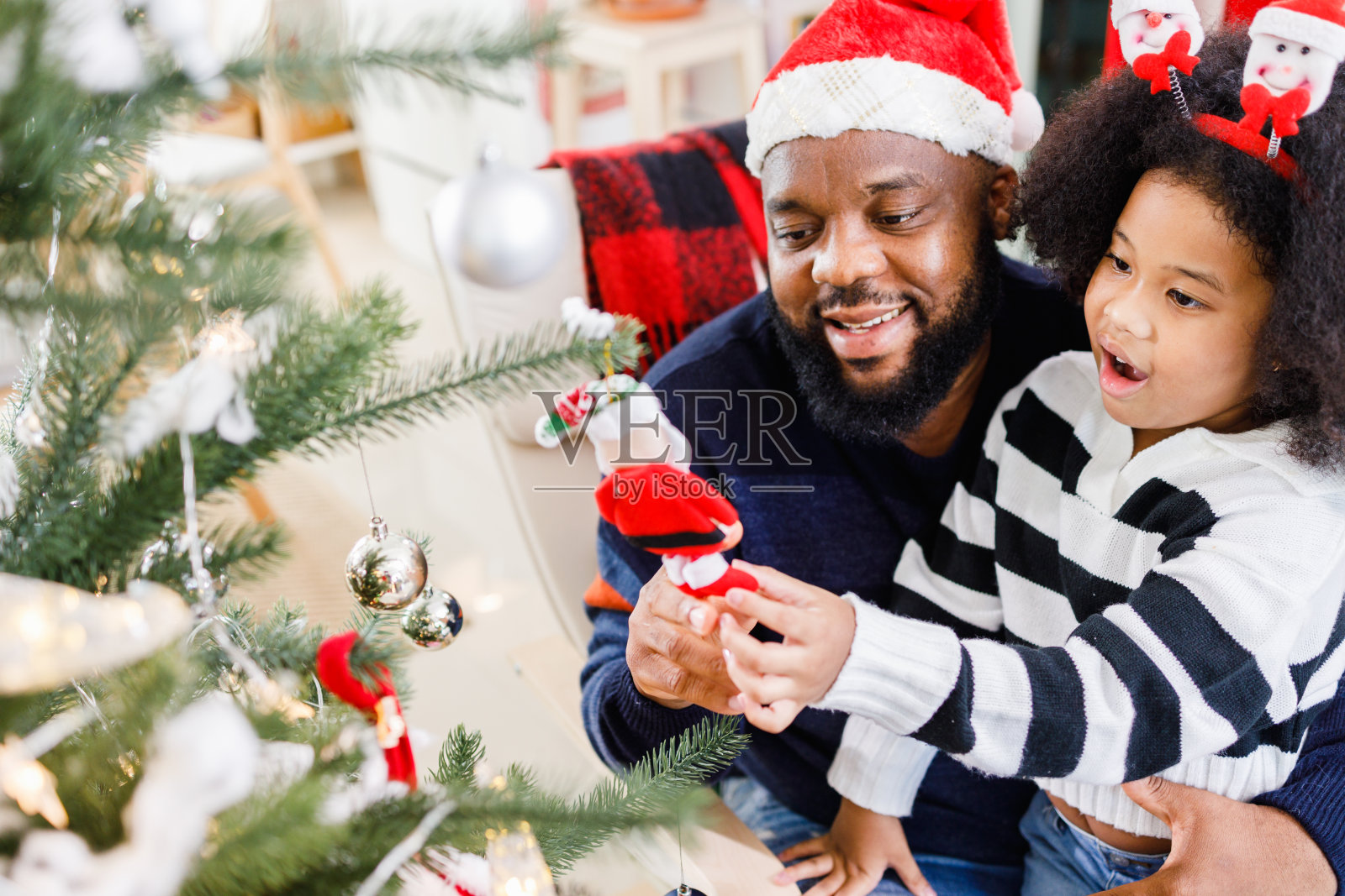 一个非裔美国家庭帮助装饰家里的圣诞树。圣诞快乐。照片摄影图片
