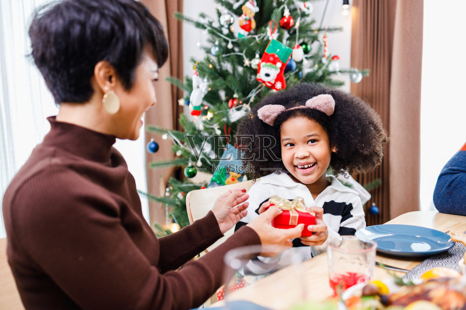 非裔美国家庭在圣诞节晚餐时惊喜地一起带着礼物。圣诞快乐。幸福的家庭。照片摄影图片